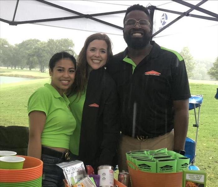 2 marketing team members with owner Alison Zelaya under their tent at a local Golf Tournament.