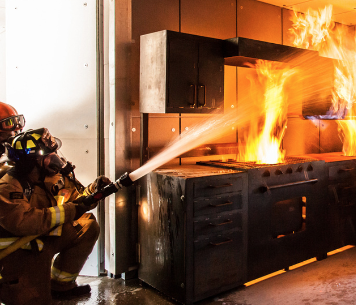 Firemen attempting to put out a kitchen fire.
